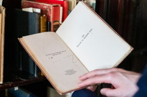 Hands hold open a small book revealing the title text, "The Ballad of Reading Gaol"