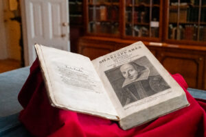 A large volume laying open on a desk revealing an etching of WIlliam Shakespeare.